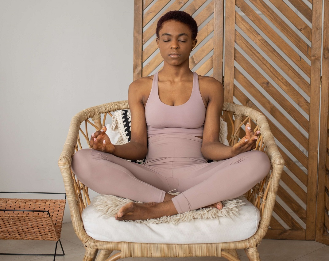 Mujer negra sentada en una silla mientras practica yoga