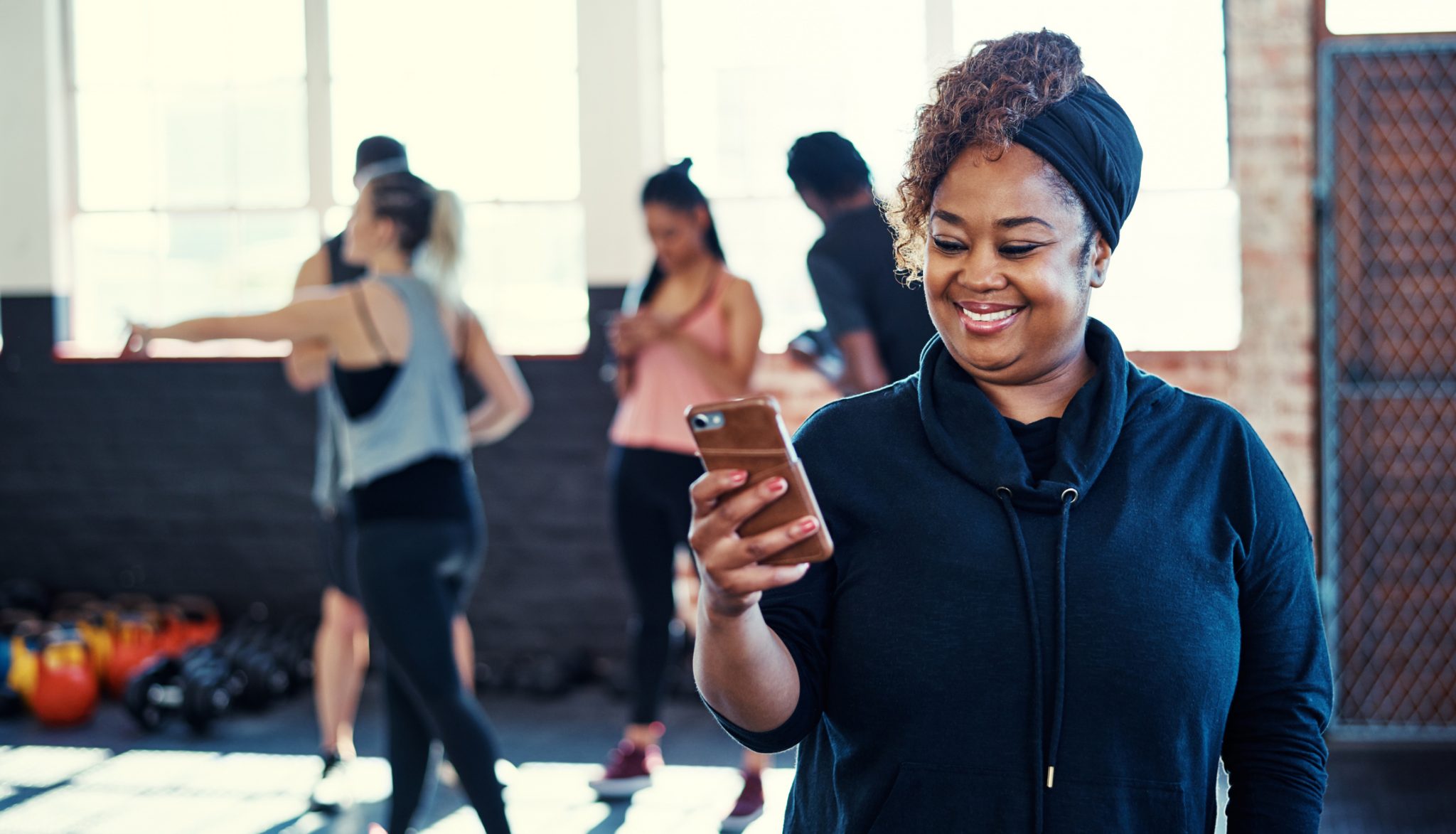 Woman looking at her phone and smiling before an exercise class